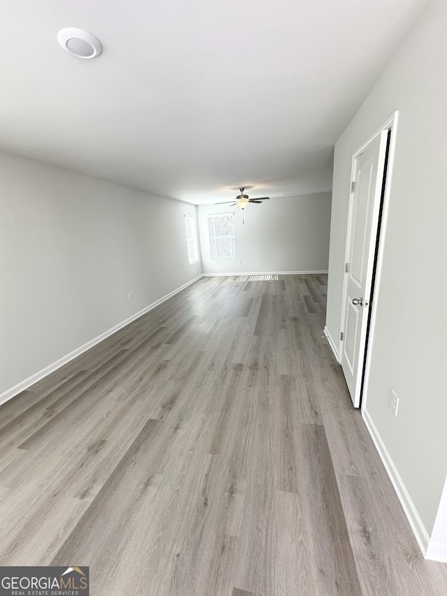 spare room with ceiling fan, wood finished floors, and baseboards