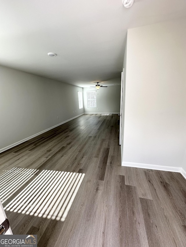 spare room featuring wood finished floors, a ceiling fan, and baseboards