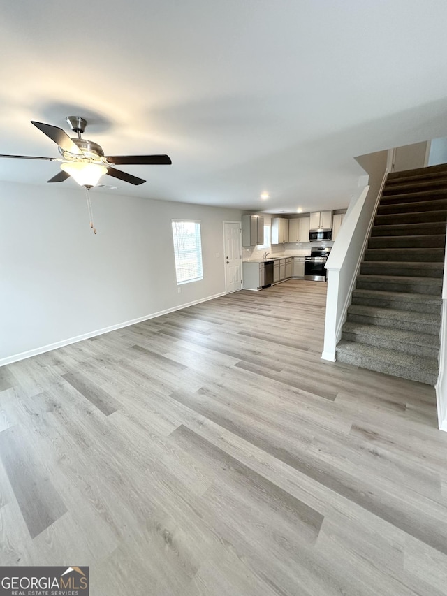 unfurnished living room with stairs, a ceiling fan, light wood-style flooring, baseboards, and recessed lighting