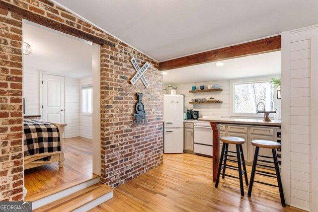 527 Main St, Suwanee, GA 30024 - kitchen featuring light wood finished floors, dishwashing machine, open shelves, brick wall, and freestanding refrigerator