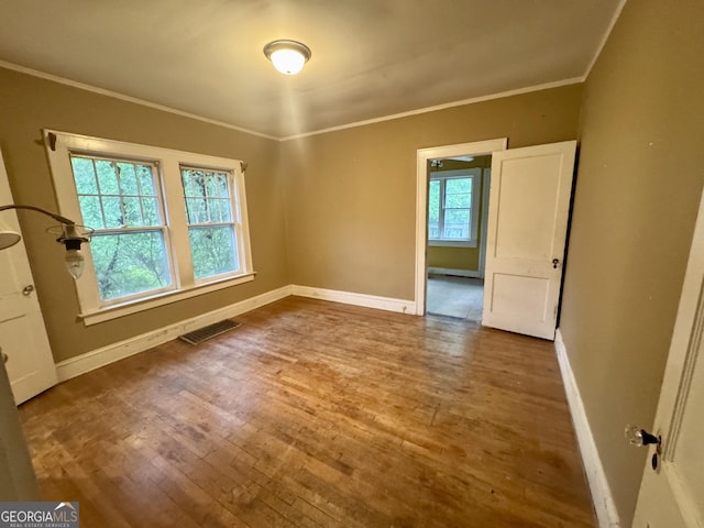 spare room with wood finished floors, baseboards, and ornamental molding