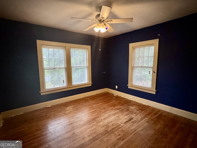unfurnished room featuring plenty of natural light, baseboards, wood finished floors, and ceiling fan