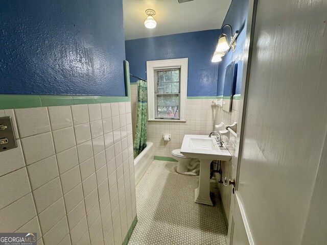 full bathroom with tile walls, toilet, tile patterned floors, a wainscoted wall, and shower / bath combo