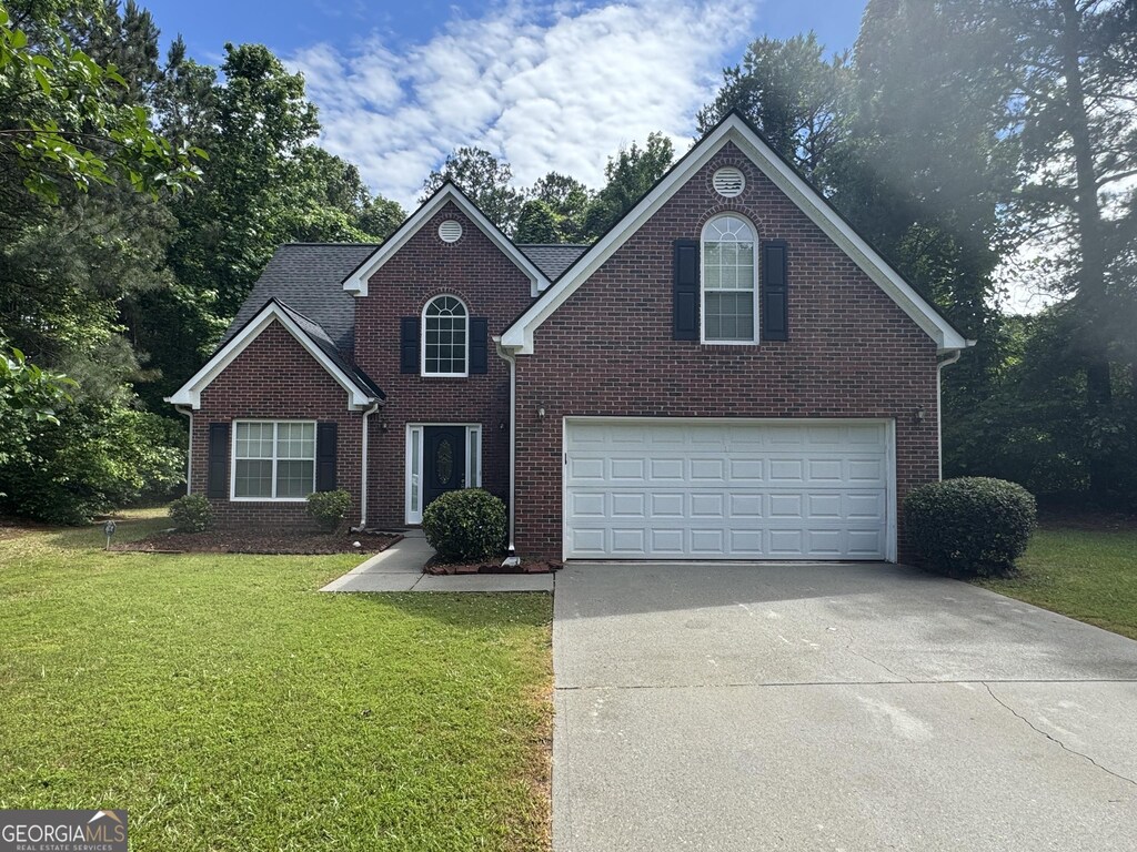 4551 Mitchells Meadow Ln, Ellenwood, GA 30294 - traditional-style house featuring driveway, a front yard, brick siding, and a garage