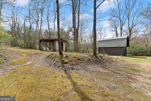 view of yard with a detached carport, an outdoor structure, and a pole building