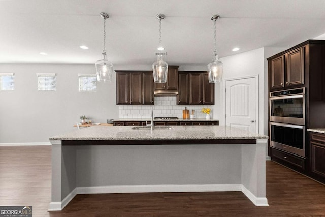 7995 Brewton Creek Dr, Cumming, GA 30028 - kitchen with stainless steel appliances, a sink, an island with sink, dark brown cabinetry, and decorative backsplash