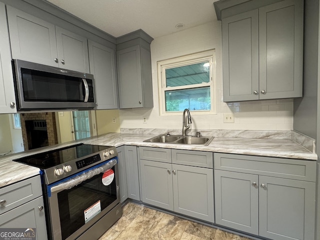kitchen with appliances with stainless steel finishes, gray cabinets, and a sink