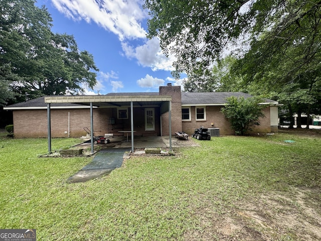rear view of house with a chimney, a lawn, brick siding, and central AC