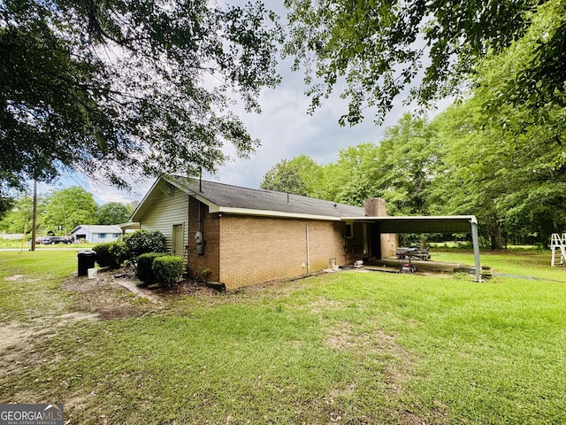 view of side of property featuring brick siding, a lawn, and a chimney
