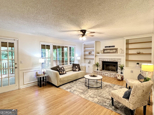 1461 Fox Forest Ter SW, Lilburn, GA 30047 - living room featuring a textured ceiling, ceiling fan, ornamental molding, light wood finished floors, and a fireplace with raised hearth