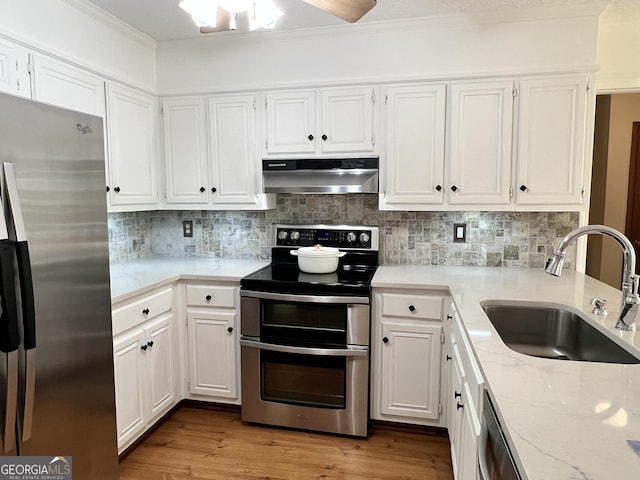 1461 Fox Forest Ter SW, Lilburn, GA 30047 - kitchen featuring appliances with stainless steel finishes, under cabinet range hood, a sink, ornamental molding, and white cabinetry