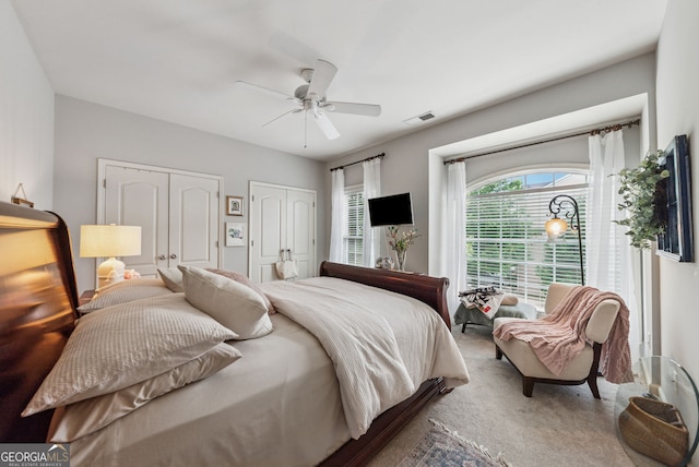 carpeted bedroom with two closets and a ceiling fan