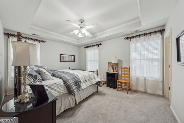 bedroom featuring a tray ceiling, crown molding, light carpet, a ceiling fan, and baseboards