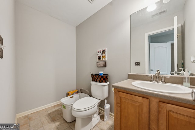bathroom with toilet, vanity, and baseboards