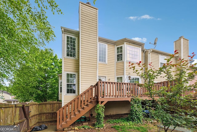 rear view of property with a chimney, fence, a deck, and stairs