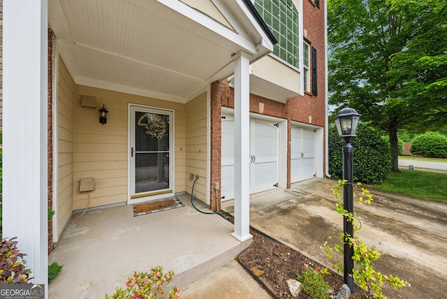 entrance to property featuring brick siding, a garage, and driveway
