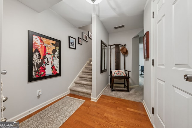 hallway with light wood finished floors, stairs, and baseboards