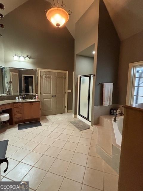 full bath featuring high vaulted ceiling, tile patterned floors, a stall shower, a garden tub, and vanity
