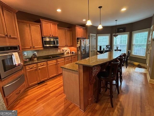 kitchen featuring stainless steel appliances, a warming drawer, light wood-style floors, recessed lighting, and tasteful backsplash