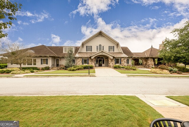 6821 Bungalow Rd, Flowery Branch, GA 30542 - view of front facade with stone siding, a gambrel roof, a front yard, metal roof, and a standing seam roof