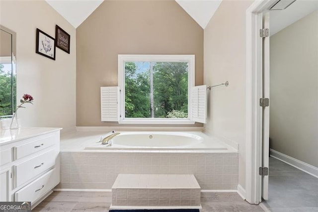 full bathroom with a garden tub, vaulted ceiling, and vanity