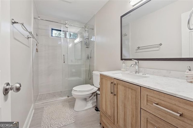 bathroom with a stall shower, toilet, vanity, and tile patterned floors
