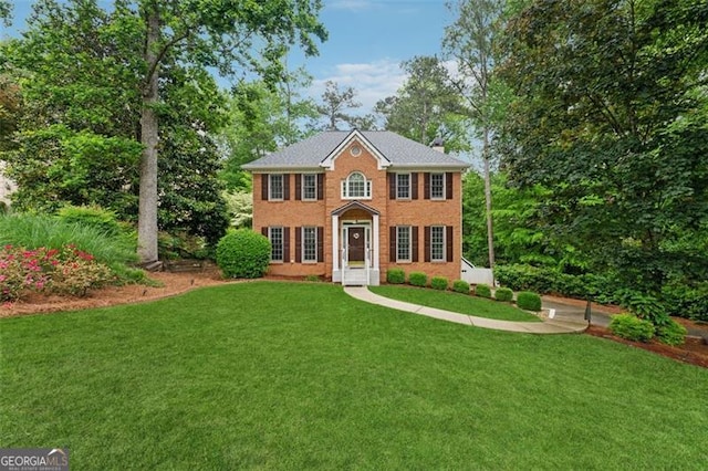 colonial house with a front lawn, brick siding, and a chimney
