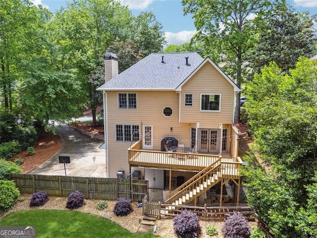 back of house featuring stairs, a deck, a chimney, fence, and french doors