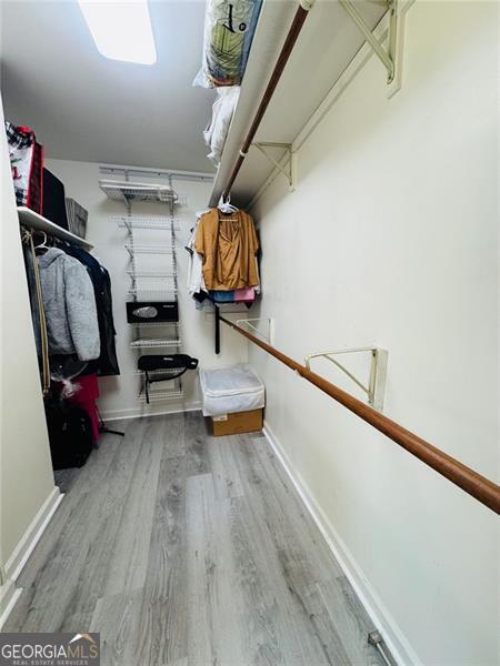 walk in closet with wood finished floors