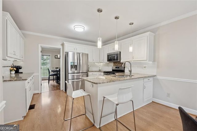 kitchen featuring appliances with stainless steel finishes, a peninsula, decorative backsplash, white cabinetry, and crown molding