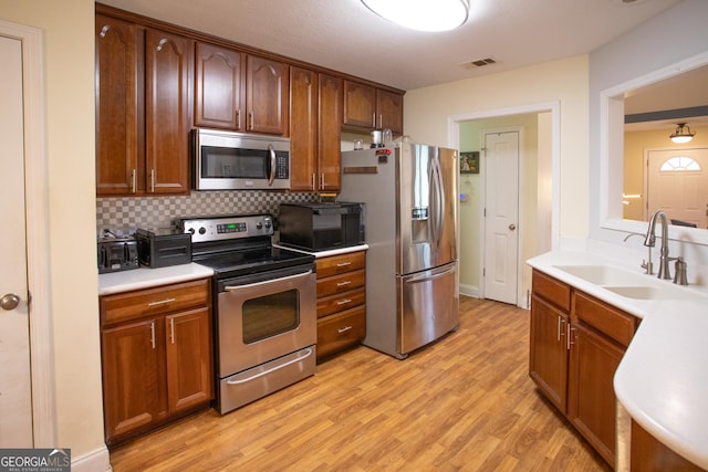 4 E Moore St, Statesboro, GA 30458 - kitchen featuring stainless steel appliances, a sink, light wood-type flooring, backsplash, and light countertops