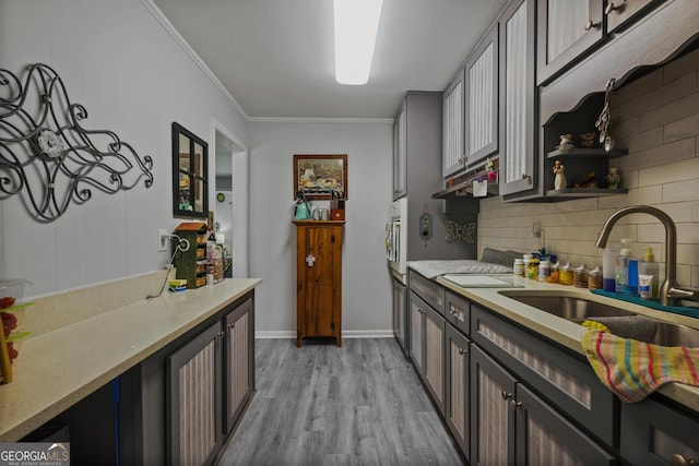 kitchen with a sink, tasteful backsplash, light wood-style floors, crown molding, and white oven