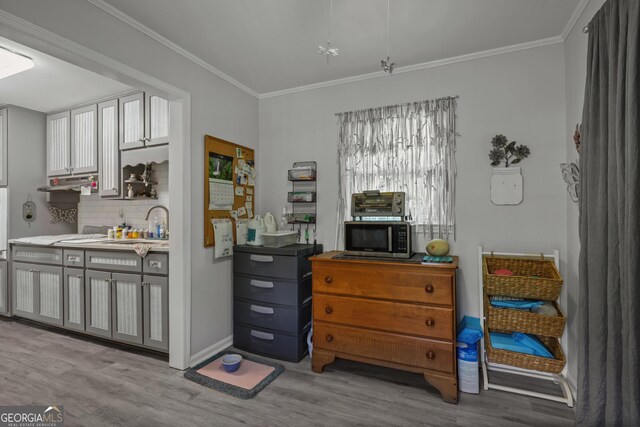 interior space with wood finished floors, stainless steel microwave, crown molding, decorative backsplash, and under cabinet range hood