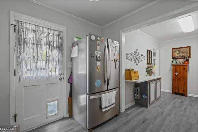 kitchen with freestanding refrigerator, wood finished floors, crown molding, baseboards, and light countertops