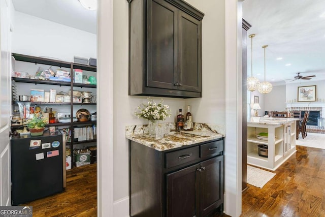 indoor dry bar featuring dark wood-style floors, a ceiling fan, and pendant lighting