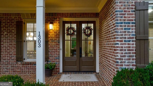 doorway to property with french doors, brick siding, and a porch