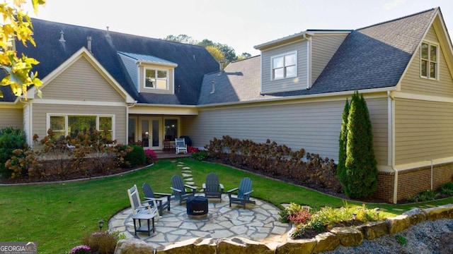 rear view of house with french doors, a patio, a fire pit, a yard, and roof with shingles