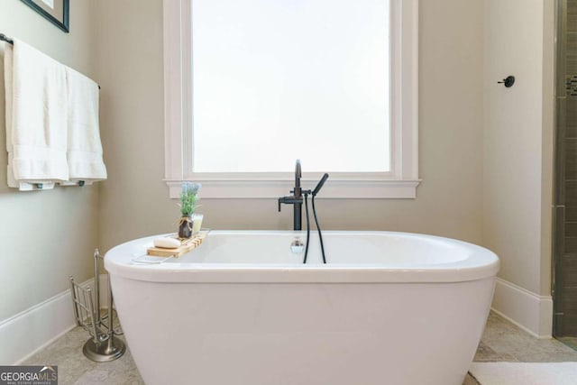 bathroom with plenty of natural light, baseboards, and a freestanding tub