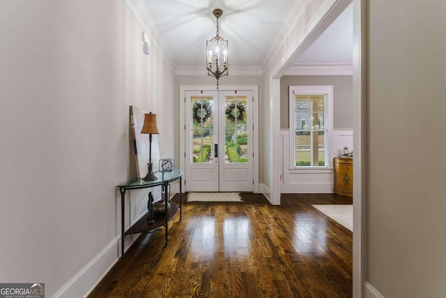 foyer entrance featuring a chandelier, wood finished floors, ornamental molding, french doors, and wainscoting