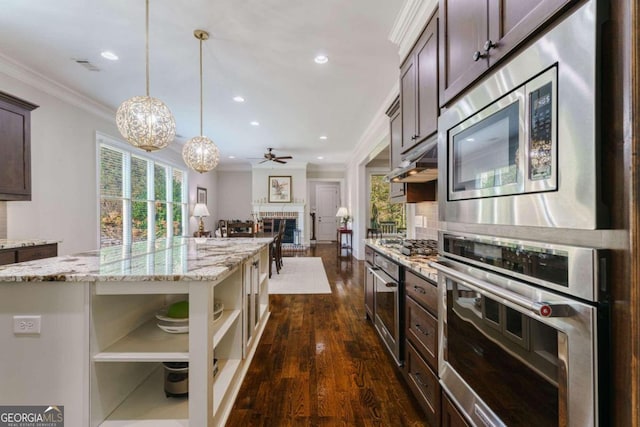 kitchen featuring stainless steel appliances, open shelves, dark brown cabinets, a brick fireplace, and crown molding
