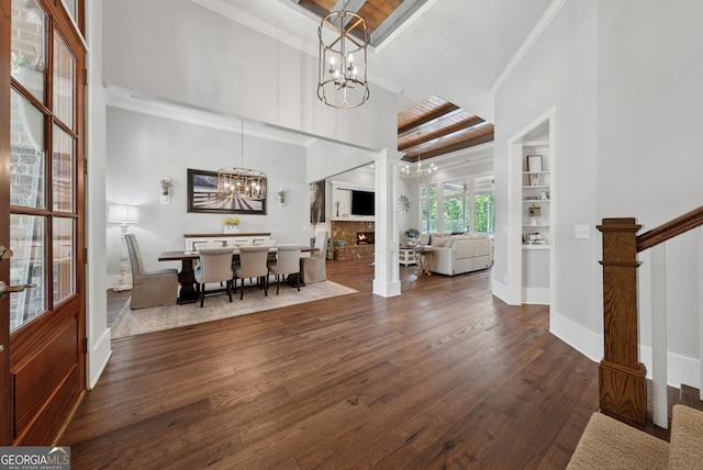 dining area featuring a chandelier, wood finished floors, baseboards, beam ceiling, and crown molding