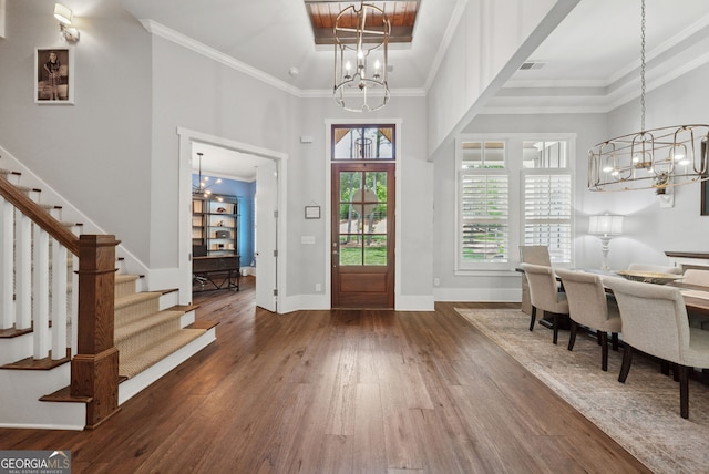entryway with a chandelier, stairs, wood finished floors, crown molding, and a towering ceiling