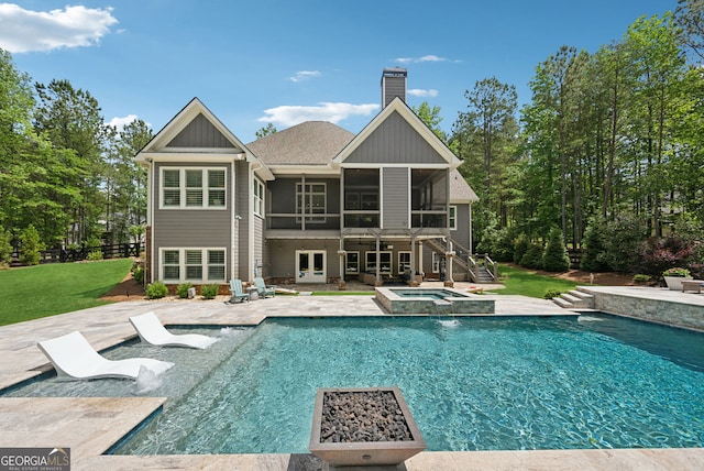 back of house with a sunroom, a patio area, a chimney, french doors, and a lawn