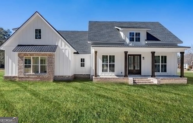 rear view of property featuring board and batten siding, a shingled roof, a standing seam roof, french doors, and a yard