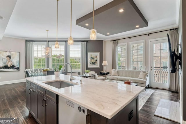 kitchen with a sink, baseboards, open floor plan, an island with sink, and crown molding