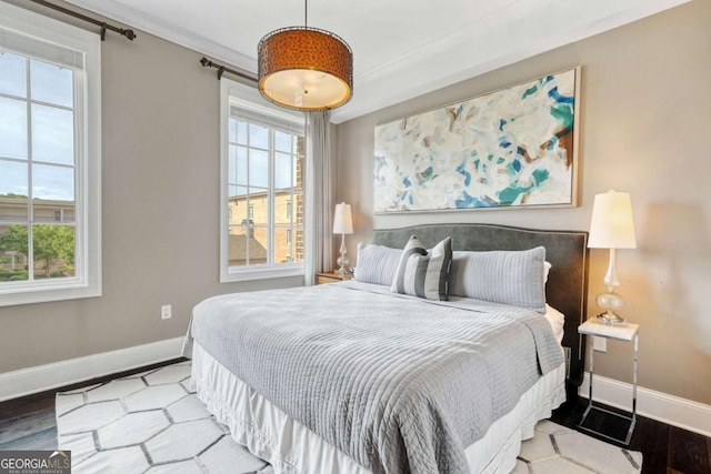 bedroom featuring baseboards, ornamental molding, and wood finished floors
