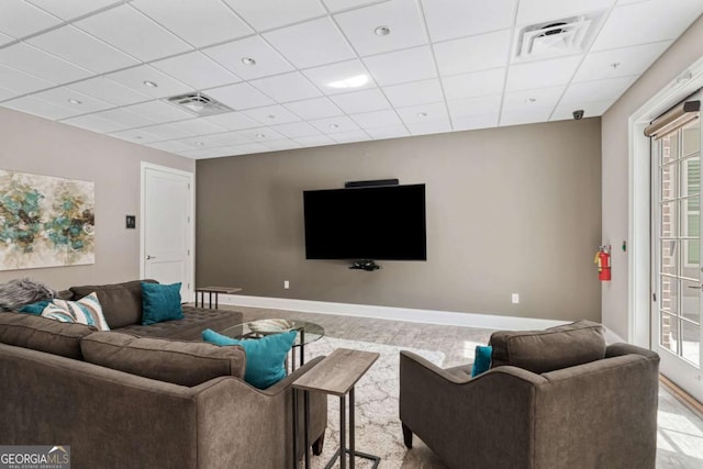 living area featuring a drop ceiling and baseboards