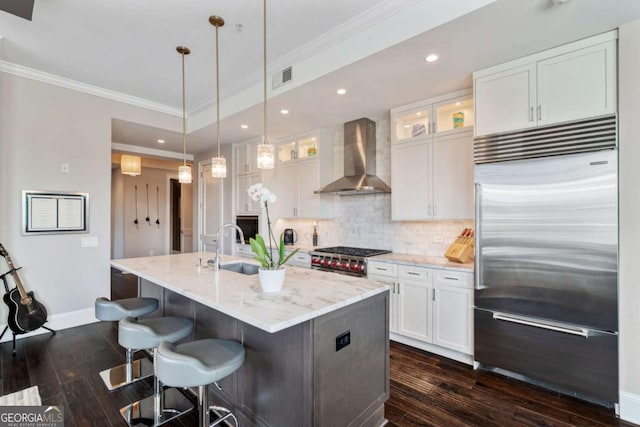 kitchen featuring high quality appliances, wall chimney exhaust hood, baseboards, dark wood-type flooring, and white cabinetry