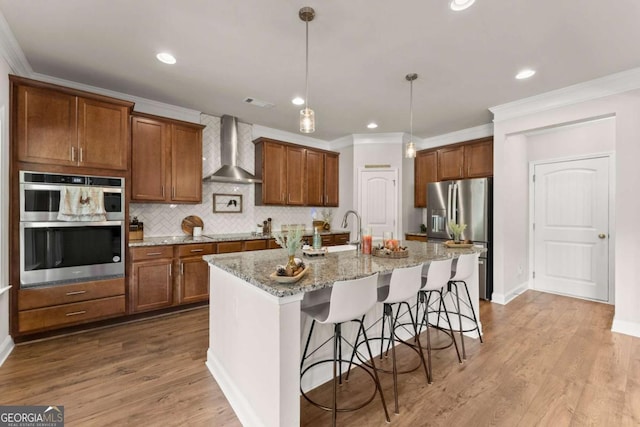 3616 Castoff Ct, Gainesville, GA 30506 - kitchen featuring appliances with stainless steel finishes, wall chimney range hood, a breakfast bar, ornamental molding, and brown cabinetry