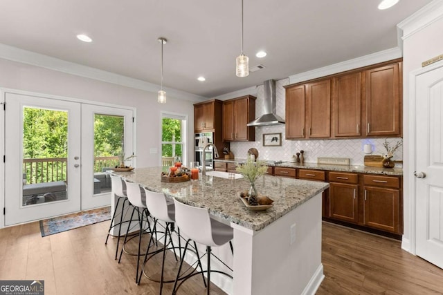 3616 Castoff Ct, Gainesville, GA 30506 - kitchen featuring wall chimney exhaust hood, a sink, a kitchen island with sink, dark wood finished floors, and a breakfast bar